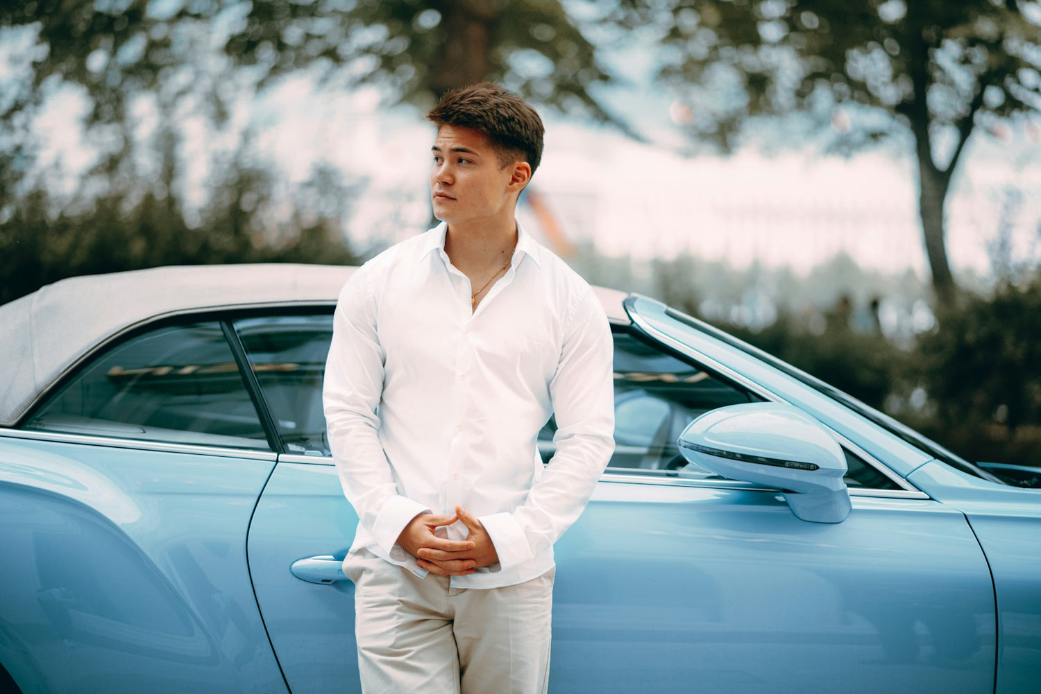 Hombre con camisa blanca junto a un auto convertible clásico